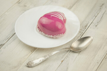 a cup and heart-shaped cake on a white wooden background