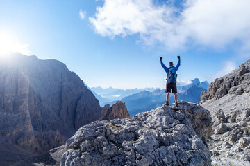 Successful person with raised arms on top of a mountain