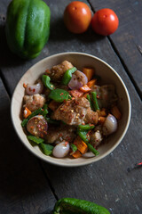 Top view of chunks of chicken pieces saute with vegetables and garnished with oregano and chilli flakes.