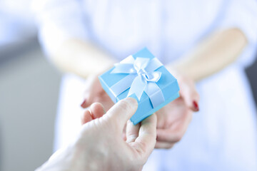 Man hand passes gift box to woman