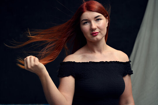 High resolution portrait of a young woman with red hair. Horizontal photo on a dark background