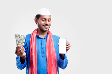 Young indian farmer showing smartphone and money on white background.