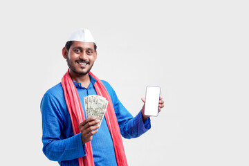 Young indian farmer showing smartphone and money on white background.