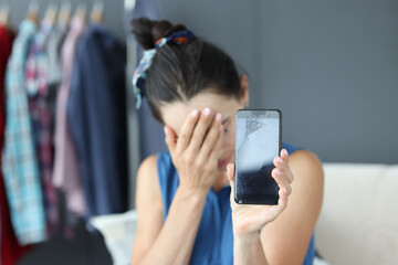 Upset woman holding a broken smartphone closeup
