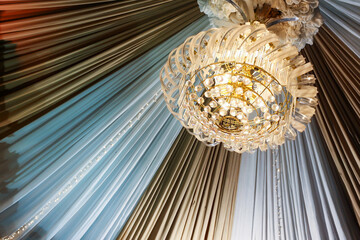 View from below close up of modern chandelier hanging from roof with decorative white and brown...