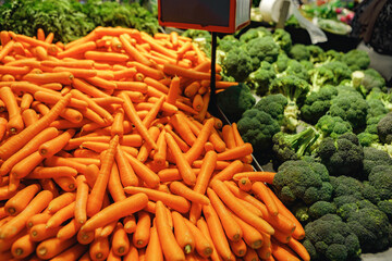 Pile of fresh carrots and broccoli on counter in supermarket