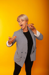 Aged American woman with white hair looks at a slice of delicious Italian pizza, surprised with her face. Dinner