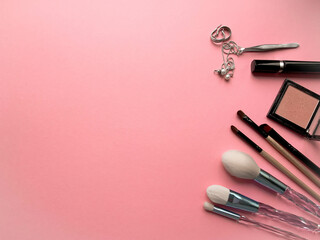 Brushes a flat lay with copy space. Beauty cosmetic makeup product layout. Stylish design. Creative fashionable concept. Cosmetics make-up brushes collection on a pink background, top view.
