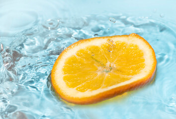 falling orange skin splashing water on a blue background