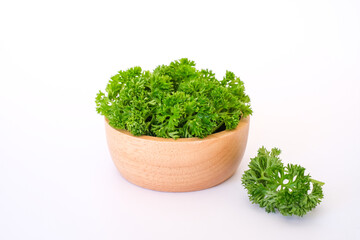 Side view composition with fresh green curley parsley leaves in the wooden bowl isolated on white...