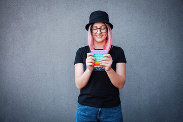 Girl with rainbow Pop It Fidget in hands. Teen Playing, Push bubble on Pop it Fidget.