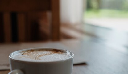Cappuccino or coffee latte on a wooden table. Close-up, selective focus, sunlight from the window. Coffee break idea, coffee break