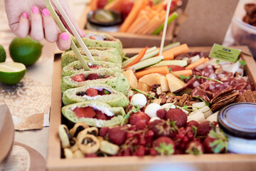 Catering box background - set with fresh green pita with strawberries, vegetables, meat and cheese. Easy way to eat for business or party.