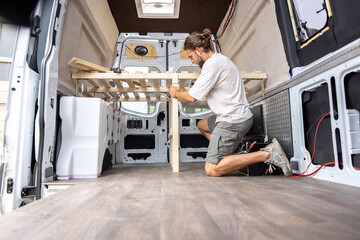 Man working on the interior of his camper van - obrazy, fototapety, plakaty