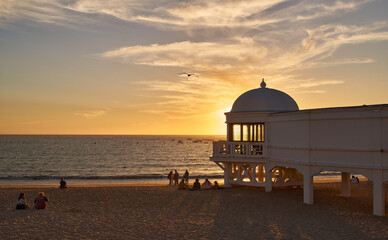 Sunset on the beach with the sun behind an old wooden building