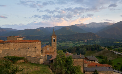 Fototapeta na wymiar Sunset in the mountains with a green meadow and an old bell tower