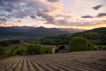 Sunset over the mountains with green meadow on the tiles of a roof