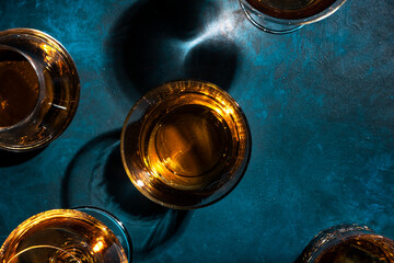 Strong alcohol drinks, hard liquors, spirits and distillates iset in glasses: cognac, scotch, whiskey and other. Blue background, top view
