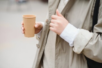 beautiful stylish woman having good fashion clothes walking on street and drinking some coffee in cup takeaway with good summer mood near street cafe.