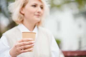beautiful stylish woman having good fashion clothes walking on street and drinking some coffee in cup takeaway with good summer mood near street cafe.
