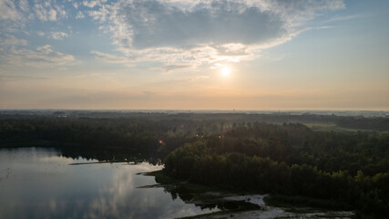 Fototapeta premium Aerial view shot by a drone of a beautiful dramatic and colorful sunset at coast of the lake. Nature landscape. Nature in Europe. reflection, blue sky and yellow sunlight. landscape during sunrise or