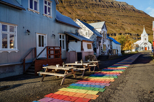 A rainbow path to the a quiet chapel in a small Icelandic town during the golden hour in autumn -- Seydisfjordur ,  Iceland