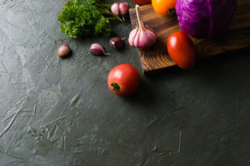 Healthy nutrition concept. Vegetables tomatoes, garlic, zucchini, cabbage, cilantro on a dark tabletop, view from the top, copy space