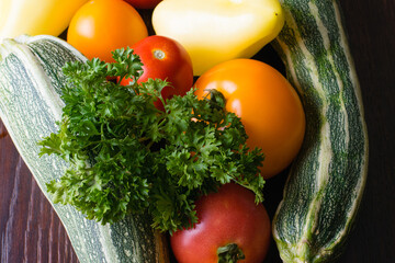 Cilantro, green taverns, yellow peppers and tomatoes on a dark wooden tabletop in rustic style