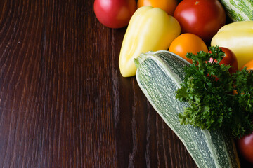 Healthy nutrition concept. Vegetables tomatoes, garlic, zucchini, cabbage, cilantro, peppers on a dark wooden table top, top view, copy space