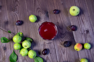 Compot made of plum and apple in glass on wooden table