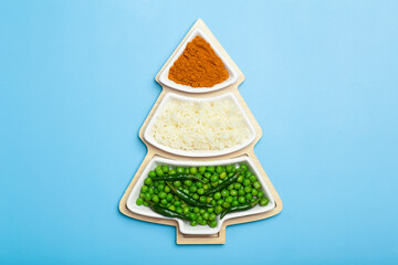 Indian flag in the shape of a new year christmas tree made from food background. Basmati rice, curry, green peas and chili peppers in the colors of the Indian flag and Christmas tree on a blue