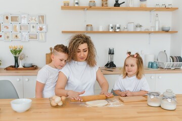 happy family in the kitchen. mother and children preparing the dough, bake cookies