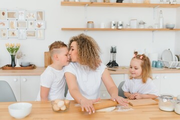 happy family in the kitchen. mother and children preparing the dough, bake cookies