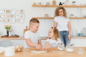 An attractive smiling family of mother, and two children, boy, girl, son, daughter cookies in a kitchen at home