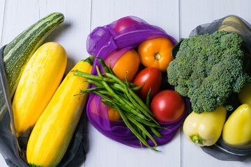 Zero waste, food shopping, eco bags for vegetables and fruits. Vegetables, broccoli, asparagus beans, courgettes, peppers and tomatoes in eco-friendly flat lay bags.