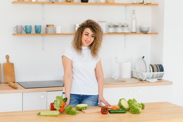 Happy young housewife mixing vegetable salad