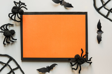 Halloween mock up with black spiders, web, bat on grey and orange frame. Flat lay, top view, copy...