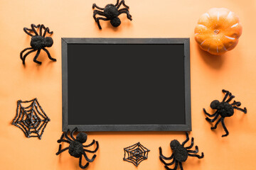 Halloween holiday blank with party decor, black spiders, web on orange. Flat lay, top view. Space for text.