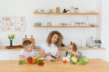 Young mother and her two kids making vegetable salad