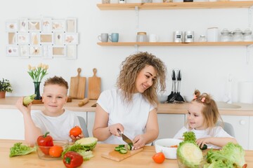 Young mother and her two kids making vegetable salad