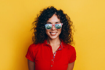 young and cheerful dark-skinned girl in a t-shirt and sunglasses points in different directions