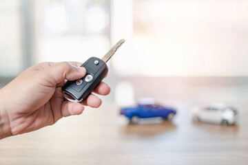 Close up hand of man holding and push remote control for lock and Un-lock car : concept model toy a car in blur background