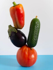 Fresh flying vegetables on a blue-white background. Eggplant, bell pepper, cucumber, tomato.