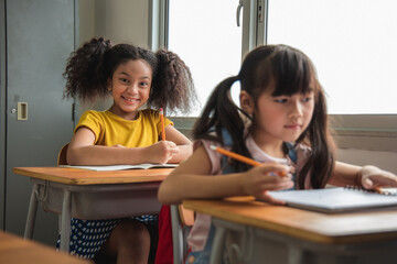 Portrait of Asian elementary school kids studying in a class. The girl Positive, Happy, smiles and look at the camera at the classroom. Back to school concept - obrazy, fototapety, plakaty