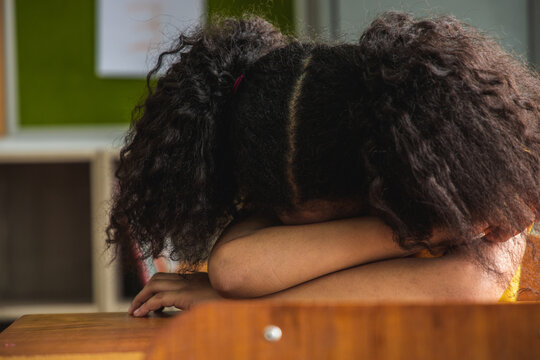 The girl african american elementary school kids asleep at classroom.