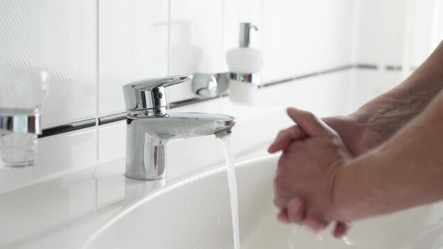 Hand washing using soap, close-up of male hands rinsing with water over bathroom sink, man rubbing hands with soap, sanitizer, coronavirus COVID-19 prevention, hygiene