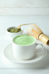 Matcha latte and accessories for making on white wooden table