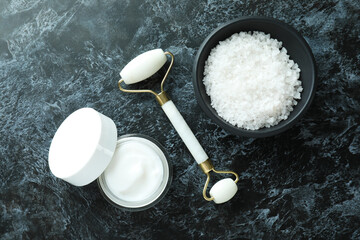 Skin care concept with face roller on black smokey table