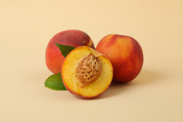 Fototapeta na wymiar Ripe peach fruits with leaves on beige background