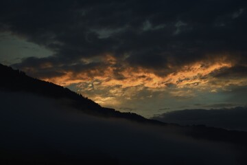 beautiful sunrise on the mountains in summer with clouds and orange colours on the sky